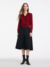A lady wears a red V-neck sweater and a skirt.